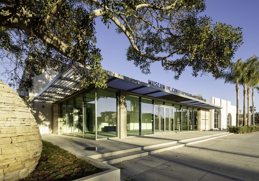 an exterior view of a modern museum building with an overhanging tree 