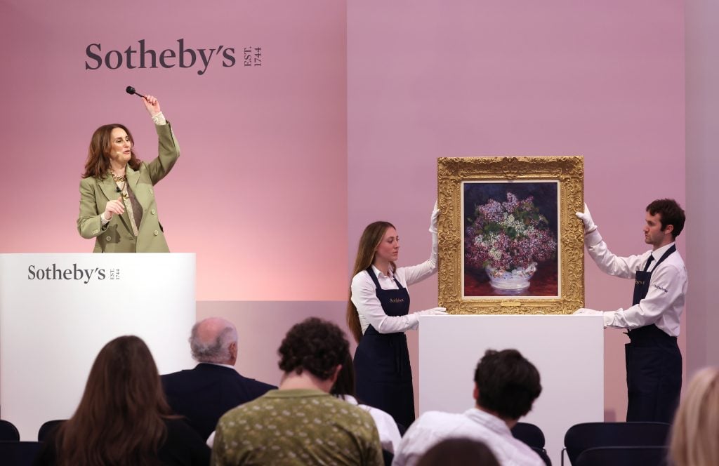 A female auctioneer holding up the gavel at an art auction