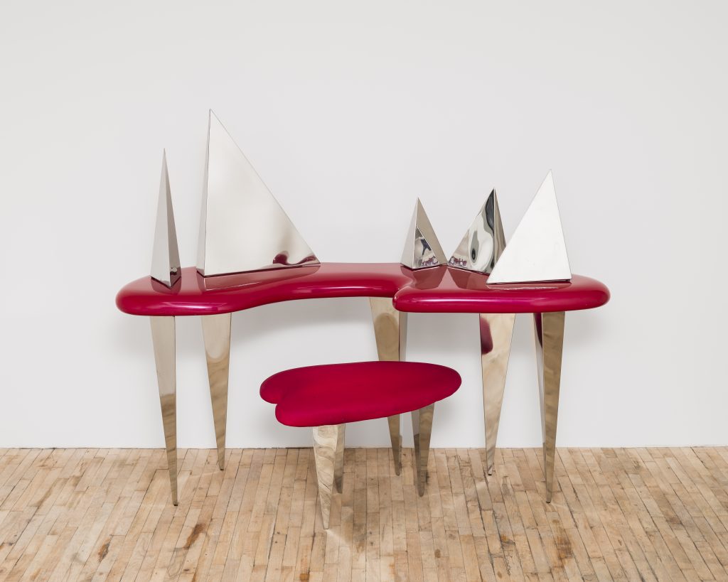 an amorphous cherry red vanity has metallic angular components 