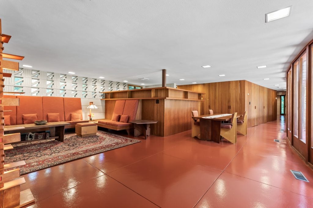 a modern interior by frank Lloyd Wrightfeaturing wood panelling with matching dining area and a red floor