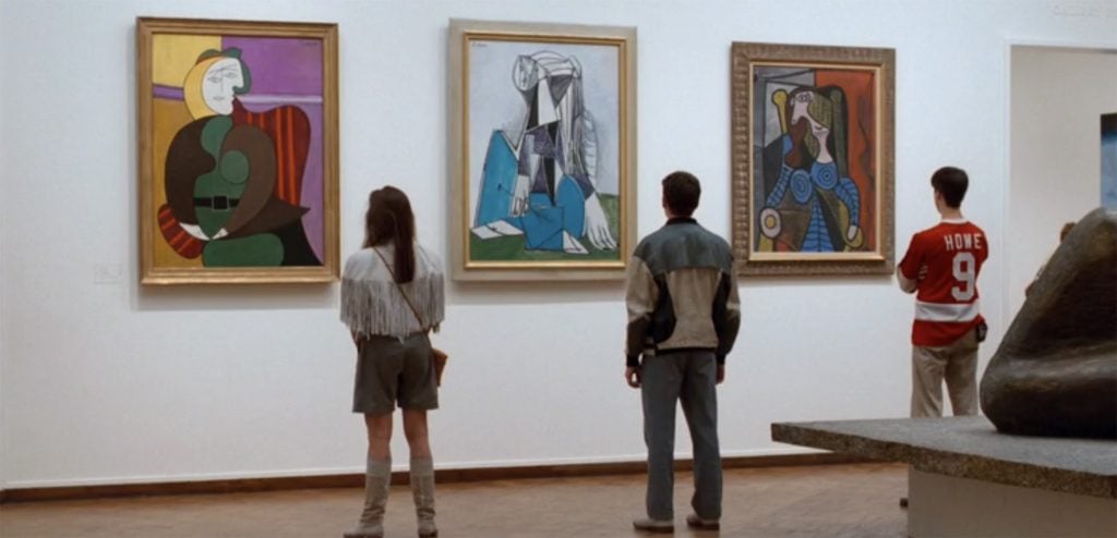 A woman and two men standing in front of three paintings at the Art Institute of Chicago.