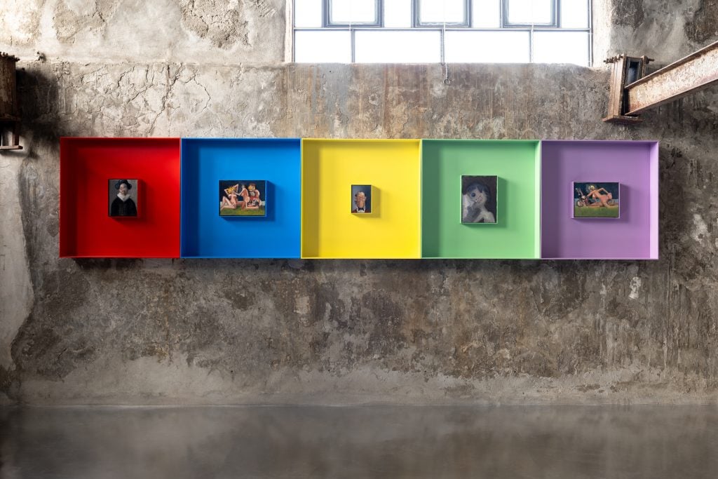 a series of small oil paintings set in wide boxes of red, blue, yellow, green, and purple