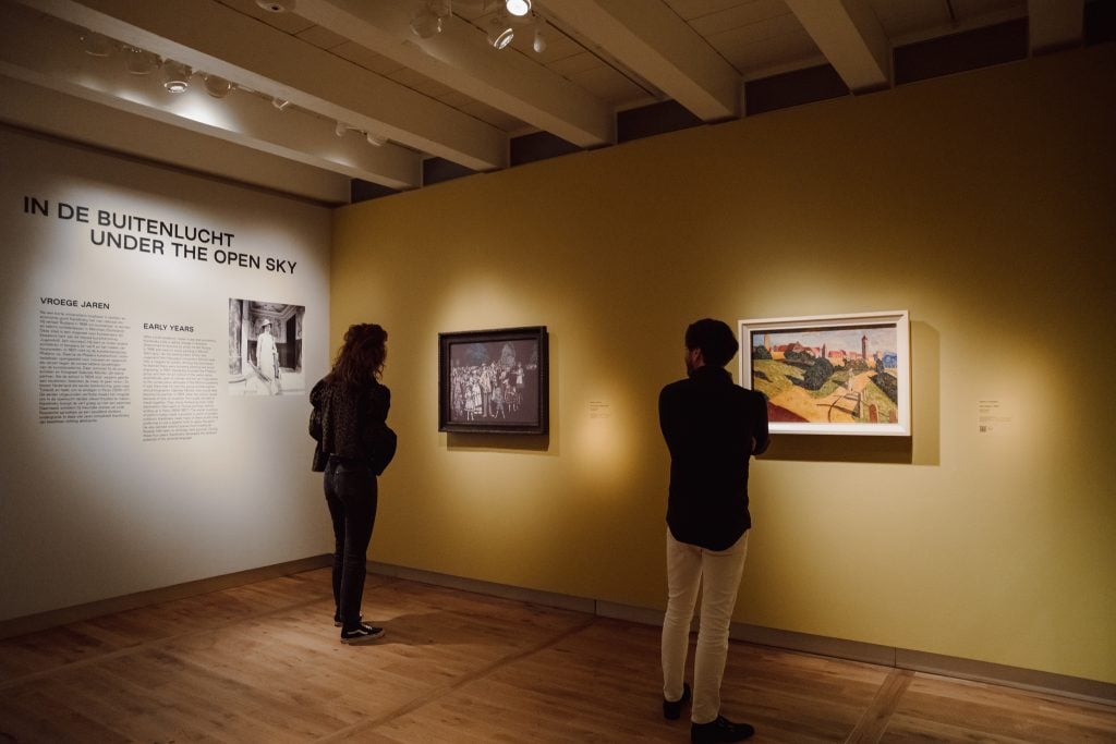 Two people standing in a gallery looking at Kandinsky paintings