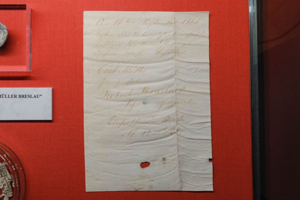 A handwritten letter from 1865 displayed against a red background