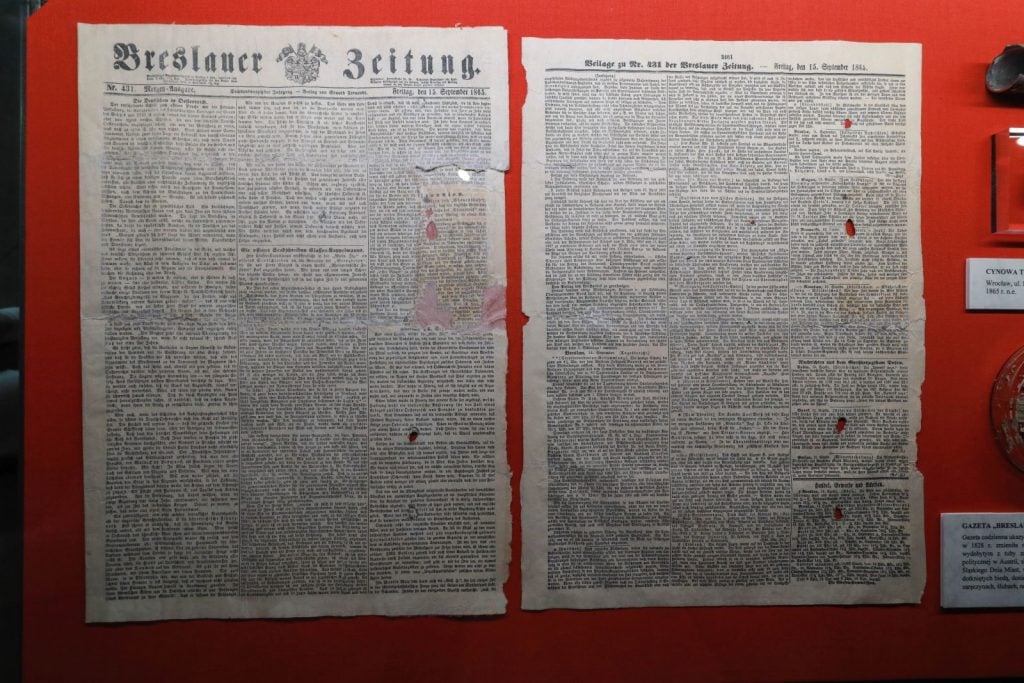 A Polish newspaper from 1865 displayed against a red background