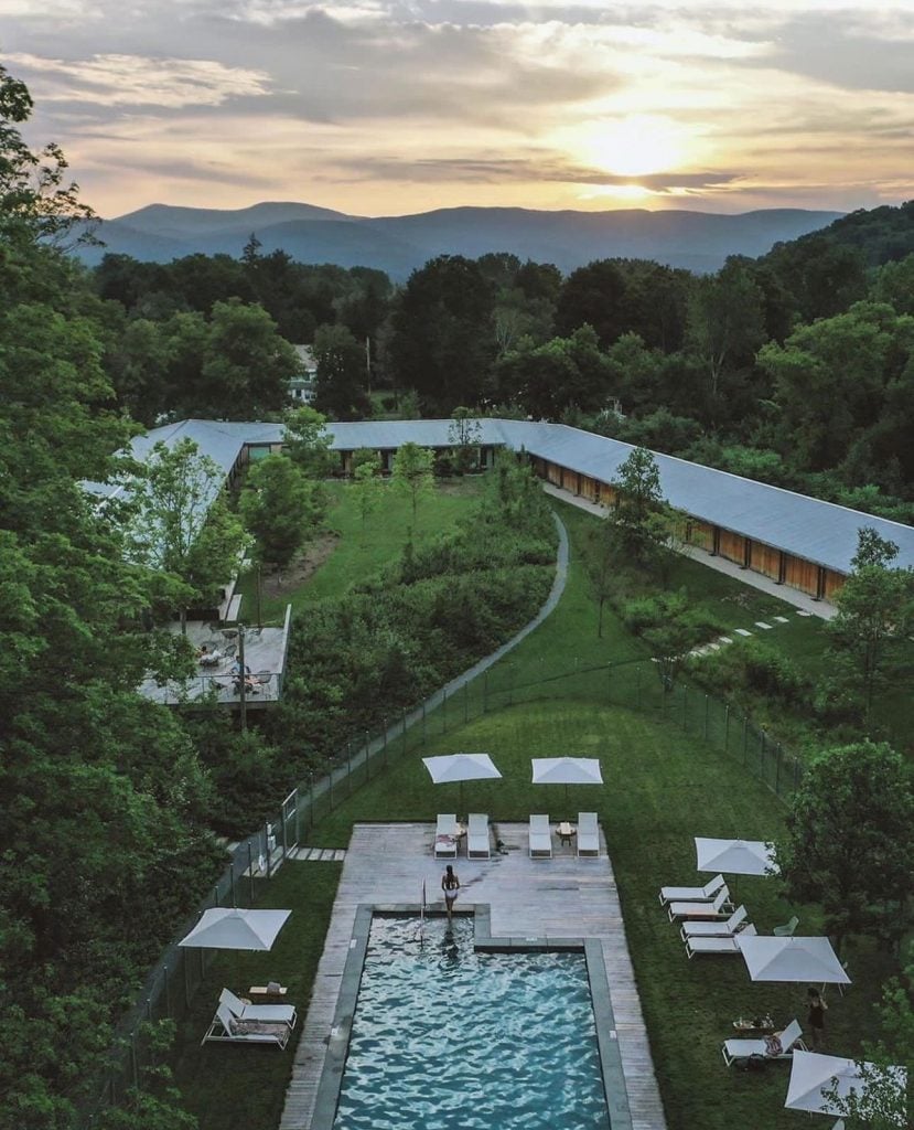 A hotel exterior with a swimming pool in a mountain valley