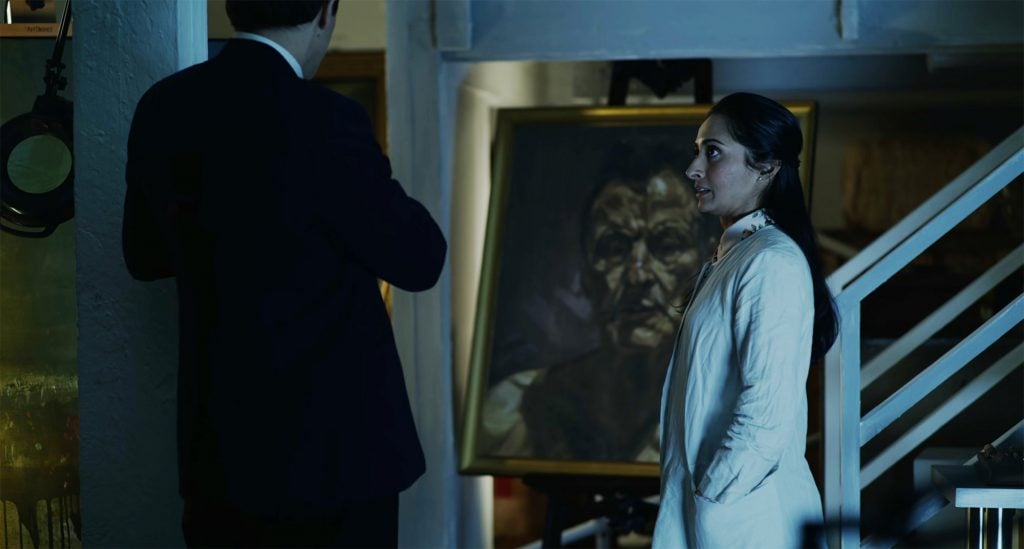 A still from the film Velvet Buzzsaw showing a man and woman gazing at a Lucian Freud portrait.