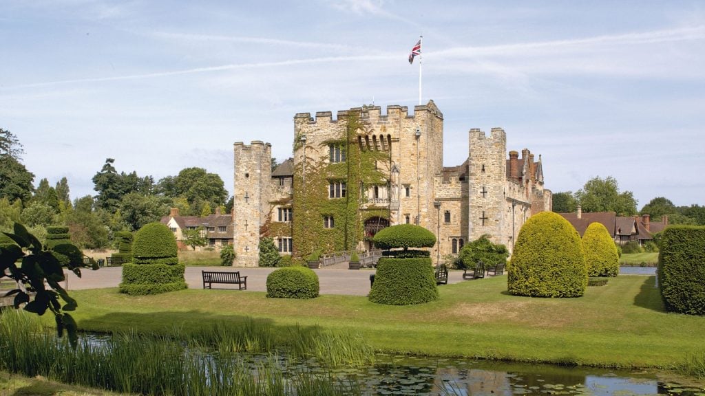 a very old castle surrounded by some well tended gardens and a moat