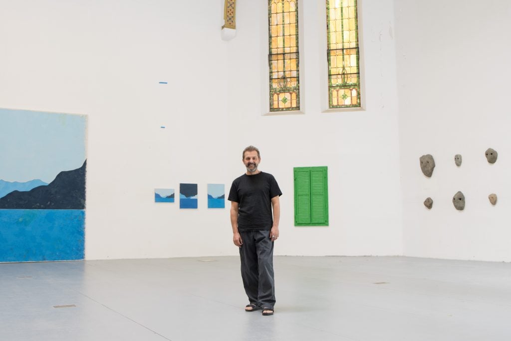 portrait of ugo rodinone standing in his studio with various artworks in the background